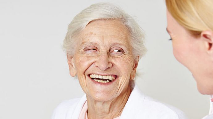 Seniorin lacht weiblicher Pflegekraft an