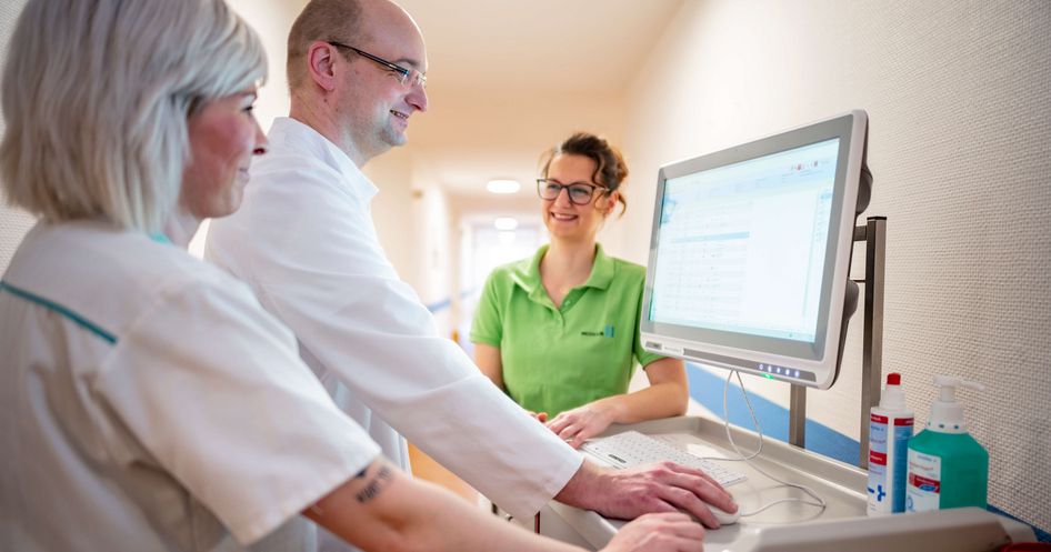Pflegekräfte und ein Arzt besprechen eine Patientenakte am Bildschirm