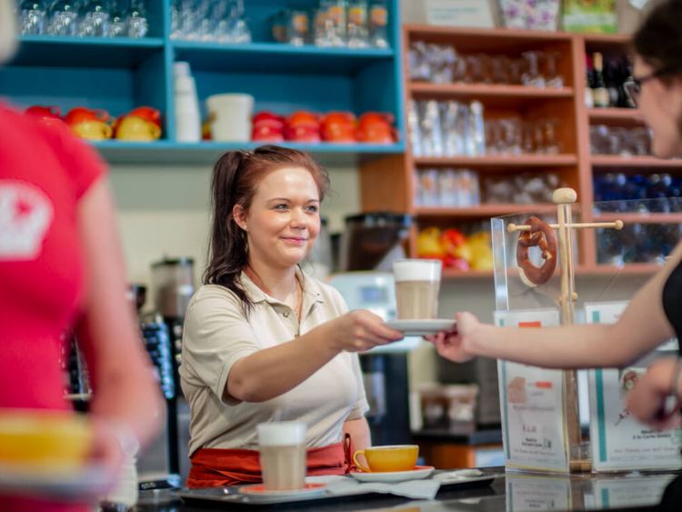 Servicekraft reicht Patienten eine Tasse Kaffee in der Cafeteria