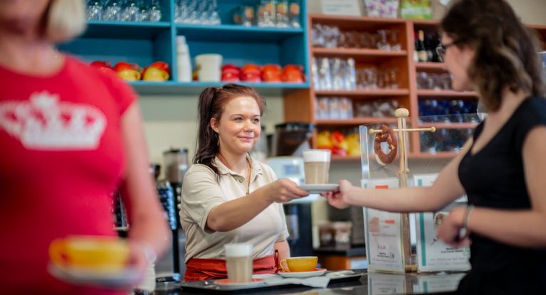 Servicekraft reicht Patienten eine Tasse Kaffee in der Cafeteria