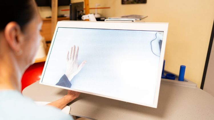 Eine Therapeutin hält ihre Hand unter ein Tyromotion-Gerät