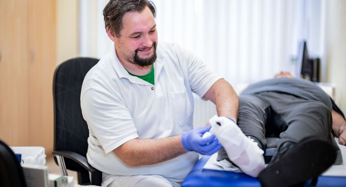 Pflegekraft verbindet einen Fuß