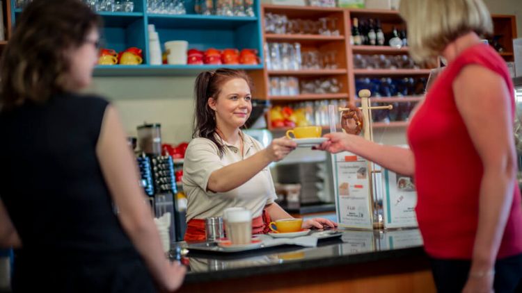 Servicekraft reicht Patienten eine Tasse Kaffee in der Cafeteria