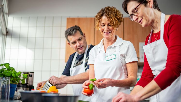 Patienten und Therapeutin kochen in der Lehrküche