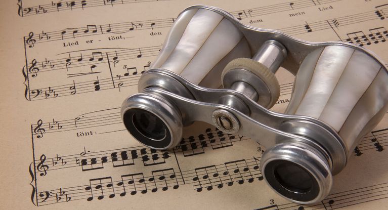 ein silbernes Opernglas liehgt auf einem Notenblatt