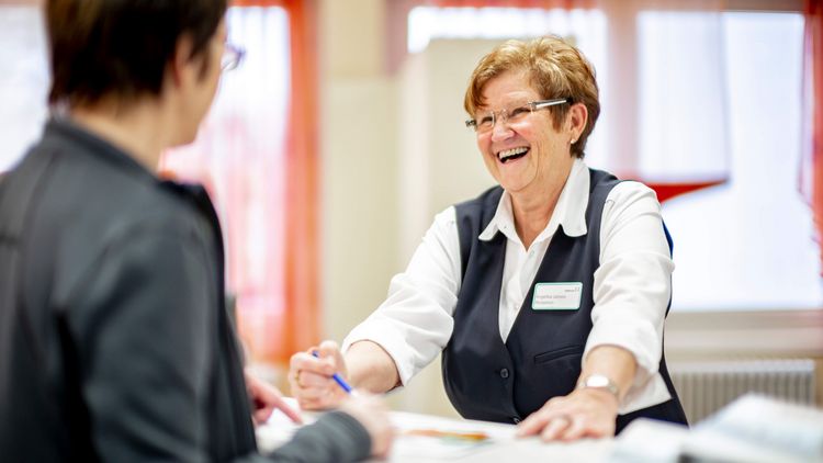 Rezeptionsmitarbeiterin begrüßt Patientin in der Klinik