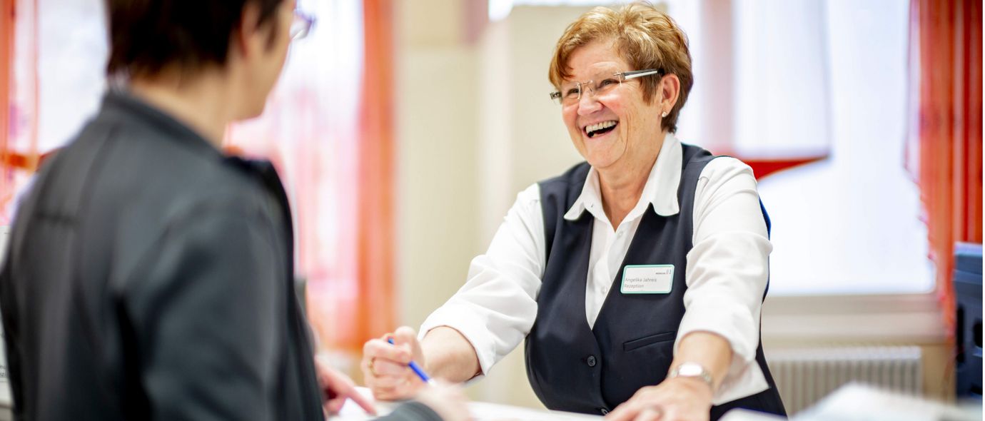 Rezeptionsmitarbeiterin begrüßt Patientin in der Klinik
