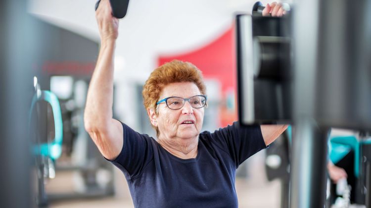 Ältere Patientin stärkt ihre Muskeln an Geräten in der medizinischen Trainingstherapie