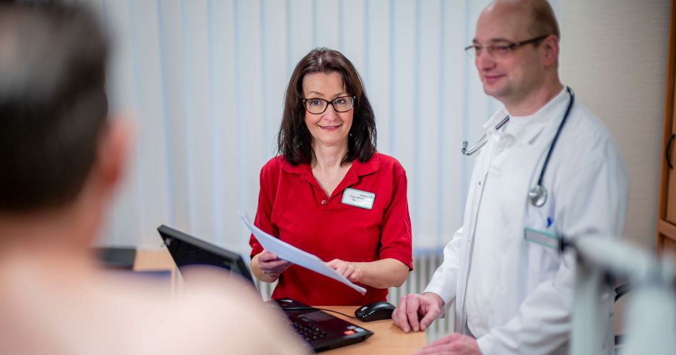 Arzt und Pflegekraft sprechen mit Patienten während der Aufnahmeuntersuchung